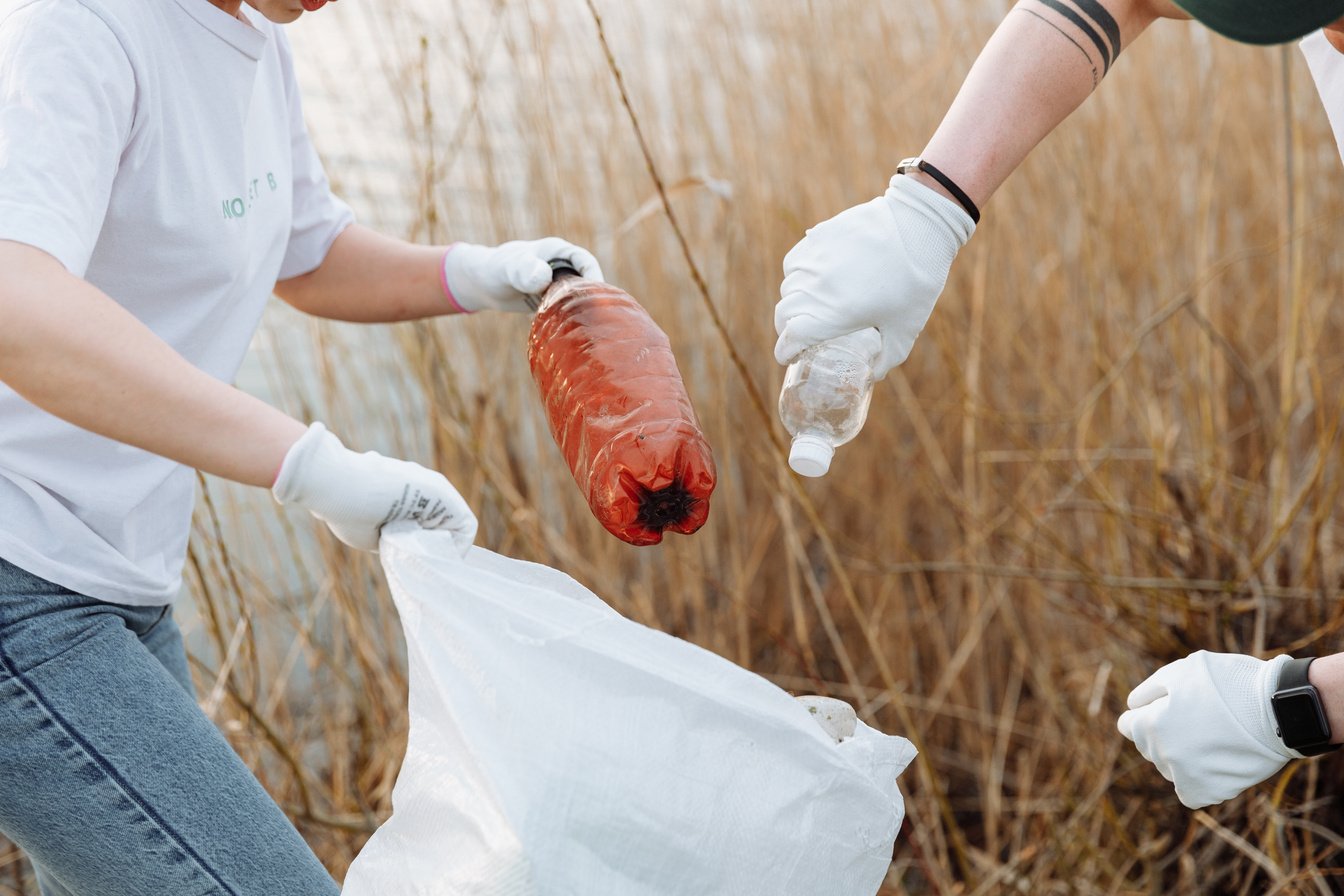 Hands of People Putting Plastic Bottles in Garbage Bag